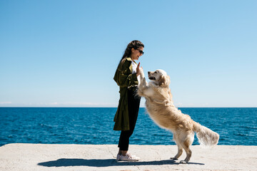 Laughing woman playing with her Labrador Retriever on a dock