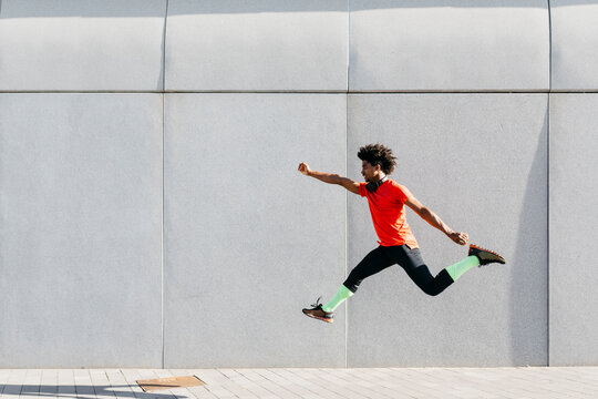 Young man doing jumps with a gray wall in the background