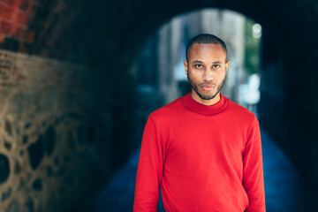Portrait of young man in an underpass wearing red pullover