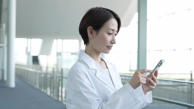 携帯を触る白衣を着た女性