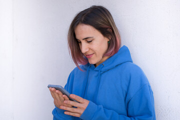 Chica rubia con mechas rosas mirando el teléfono móvil