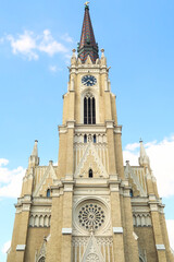 The front facade and bell, clock tower of the Name of Mary Church with its colorful roof in front...