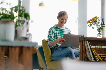 Smiling young woman using laptop in a cafe