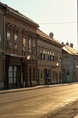 Fototapeta premium Golden hour inside the Petrovaradin Lower Fortress, sunlight is shining through the street lamps, lanterns on the facades of historic buildings and reflecting on the windows, Novi Sad, Serbia