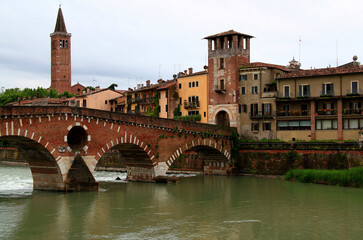 Photo of a view of the promenade of the historic part of the city of Verona, Italy, with the Adige River and a brick arch bridge across it