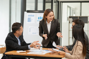 Group of Asian businessmen are presenting graphs on a whiteboard.