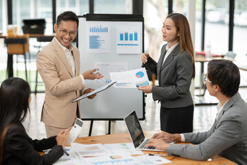 Group of Asian businessmen are presenting graphs on a whiteboard.