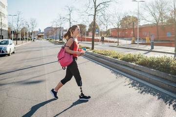 Sporty young woman with leg prosthesis walking in the city