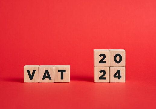 The abbreviation VAT value added tax for the year 2024 on wooden cubes with red background.