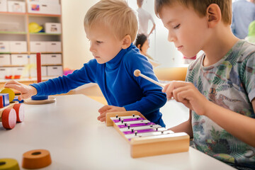 Two boys playing with musical instruments and toys in kindergarten