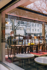 Man with mask looking through window into closed restaurant
