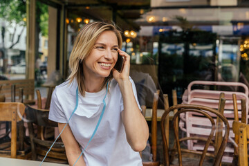 Portrait of woman on the phone with protective mask in front of a closed coffee shop