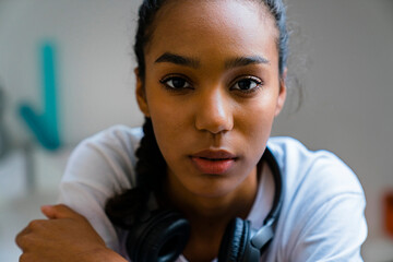 Close-up of teenage girl with headphone around neck sitting at home