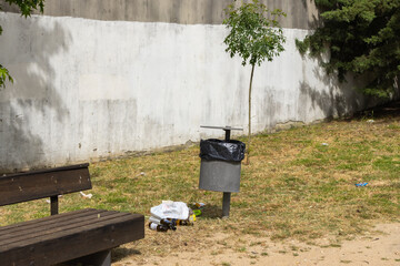 Urban park trash can overflowing with garbage