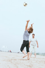 Father and little son playing with ball on the beach