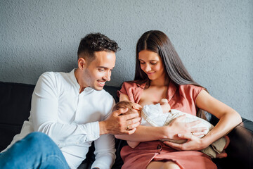 Happy father looking at baby boy being breastfed by mother at home