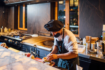 Chef wearing protective face mask preparing burgers in restaurant kitchen