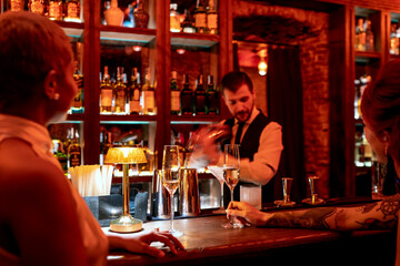 Bartender mixing cocktail while standing at bar counter in pub