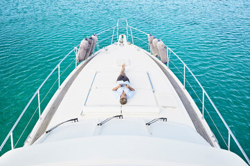 Smiling man lying on deck of his motor yacht using tablet