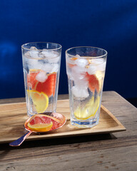 beautiful glasses with a cold drink with ice and citrus fruits on the table on a tray.