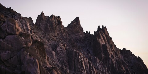 Rugged mountain face, close-up on jagged edges, sunset hues, clear sharp focus, side lighting.