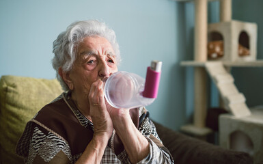 Senior woman using inhaler at home
