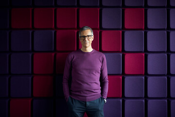 Portrait of confident businessman at a noise reduction wall in office