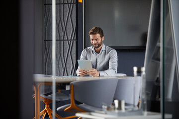 Smiling businessman using digital tablet while sitting in office