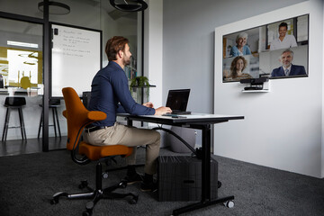 Businessman attending web conference while sitting in office