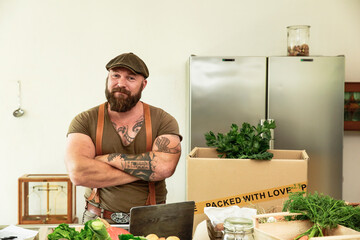 Owner of a delivery service for organic vegetables, standing proud in his kitchen
