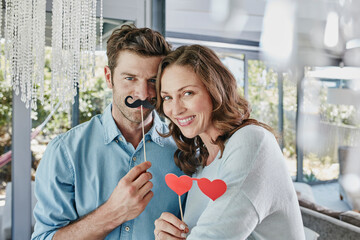 Couple with paper moustache and heart-shaped eye disguise