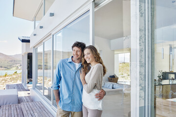 Happy couple standing at luxury beach house