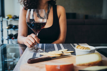 Young woman holding wineglass while sitting at dining table