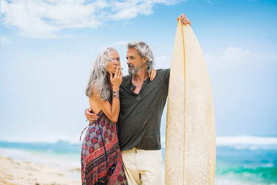 Senior hippie couple with surfboard on the beach