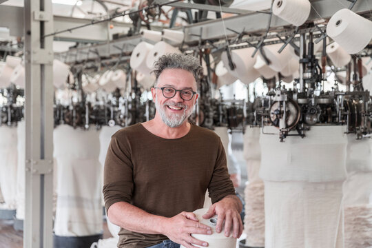 Portrait of a happy mature man in a textile factory - Powered by Adobe