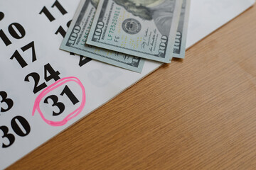 Calendar with marker marking the 31st day and dollar bills close-up, money order, postal order,...