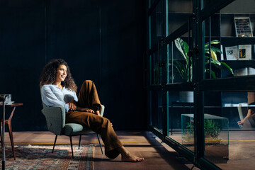 Young businesswoman looking out of window in loft office