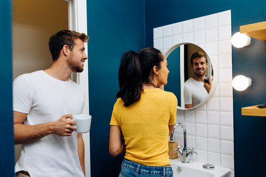 Smiling young man watching girlfriend applying make up