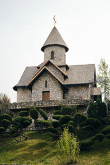 Fototapeta premium Small town Bijeljina in Bosnia and Herzegovina. Stanisici Ethno Village - popular tourist destination. Old stone orthodox church and green spring grass and plants.