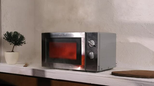 Microwave oven on fire burning and smoking in kitchen while cooking food.