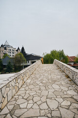 A young girl stands on a stone old bridge and enjoys the views of nature and buildings. Hotel...