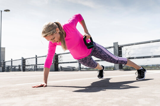 Woman training with dumbells, doing one-armed plank
