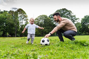 Happy father playing football with son in a park