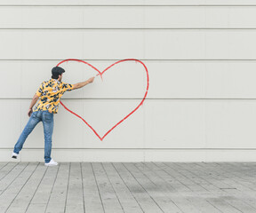 Digital composite of young man drawing aheart at a wall