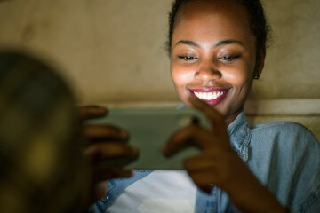Portrait of happy young woman using smartphone by night, Lisbon, Portugal