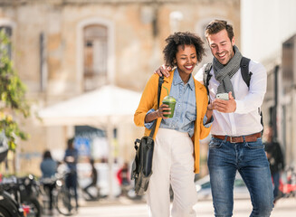 Happy young couple looking at smartphone in the city