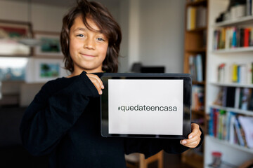 Portrait of relaxed boy presenting digital tablet with request