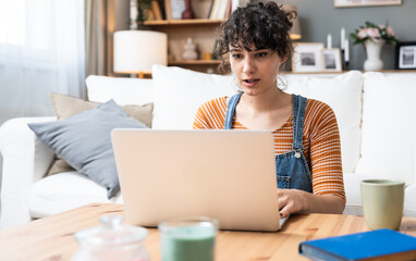 Head shot pleasant happy young woman freelancer working on computer at home. Attractive businesswoman studying online, using laptop software, web surfing information or shopping in internet store.