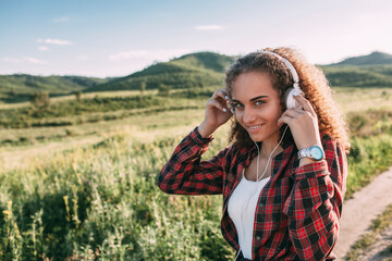 Teenage girl listening music with headphones in nature