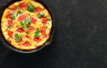 Frittata with tomatoes and spinach in frying pan